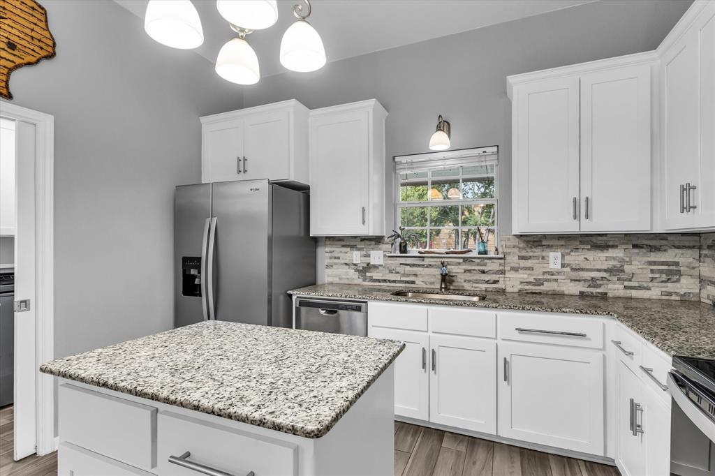 7 Market Loop Morgan's Point Resort, TX 76513 - Photo 8 of 31 Well-appointed kitchen featuring a center island with granite countertop, white cabinetry, stainless steel appliances, a tile backsplash, and wood-finish flooring