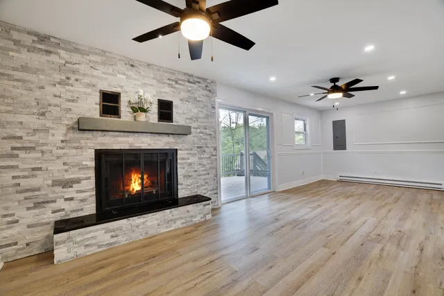 an empty room with windows a fireplace a ceiling fan and a fireplace