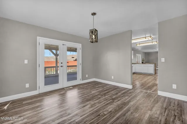 a view of an empty room with window and wooden floor
