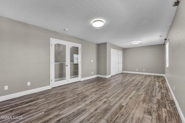 an empty room with wooden floor ceiling fan and windows