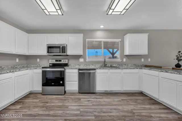 a kitchen with granite countertop a stove top oven a sink dishwasher a microwave oven and a refrigerator with wooden cabinets