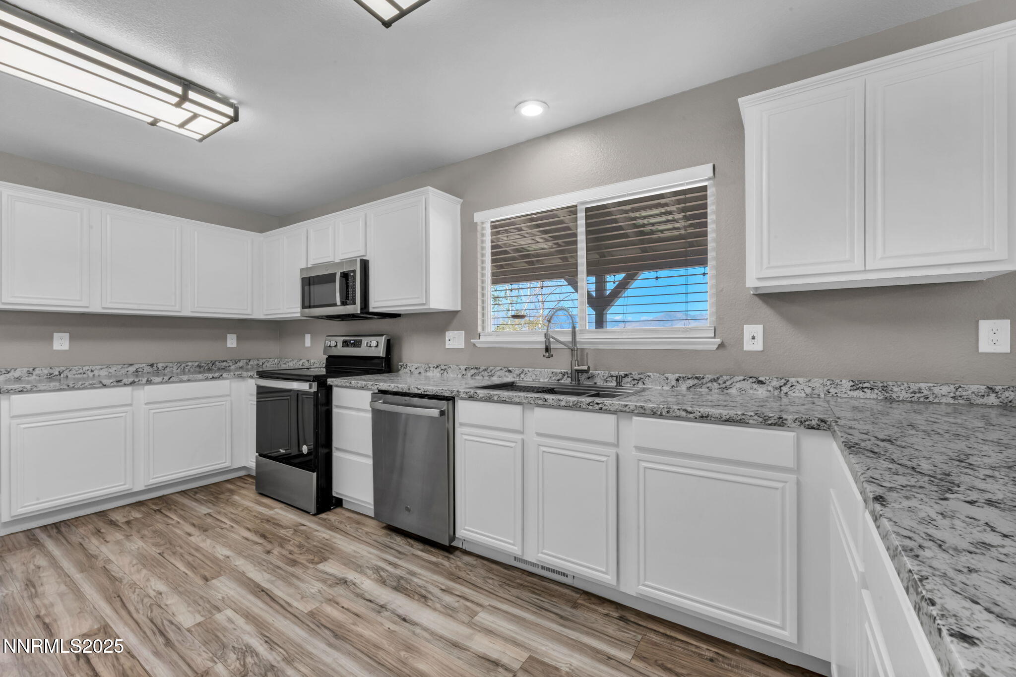 17391 Crystal Canyon Boulevard Reno, NV 89508 - Photo 7 of 63 a kitchen with granite countertop a sink stainless steel appliances and white cabinets