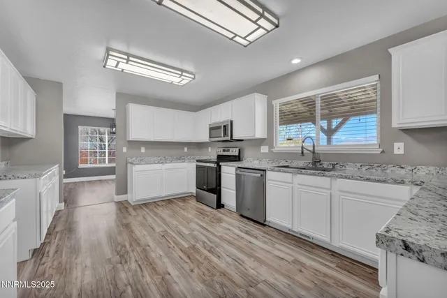 a kitchen with granite countertop a sink cabinets stainless steel appliances and a window