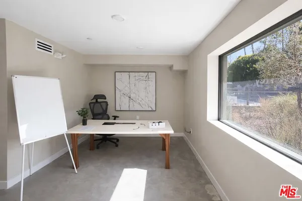 a view of a workspace with furniture and a window