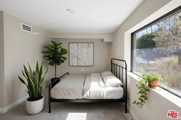 a bedroom with a large bed and a potted plant