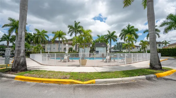 a view of a swimming pool with a yard and palm trees