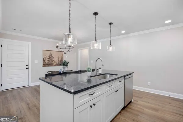a kitchen with kitchen island a dining table chairs stainless steel appliances and wooden floor
