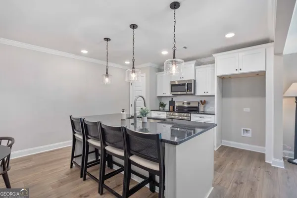 a kitchen with stainless steel appliances kitchen island granite countertop a table chairs stove and white cabinets