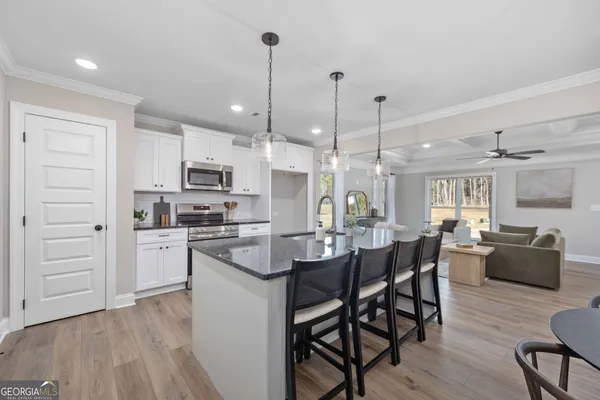 a kitchen with stainless steel appliances kitchen island granite countertop a refrigerator a stove a sink and a chandelier