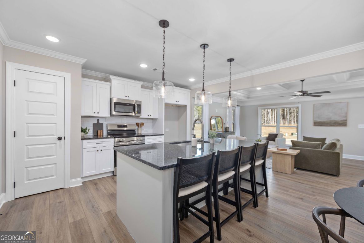 23 Rivers Edge Lane Franklin, GA 30217 - Photo 14 of 32 a kitchen with stainless steel appliances kitchen island granite countertop a table chairs stove and white cabinets