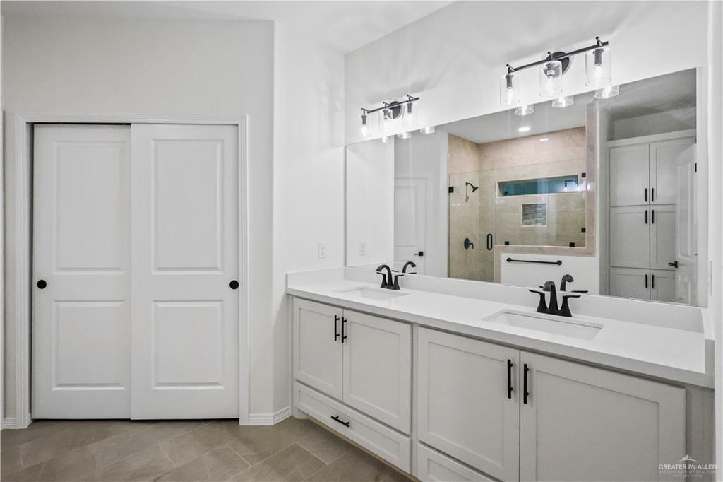 7305 North 55th Lane Mission, TX 78573 - Photo 11 of 26 a bathroom with a double vanity sink a mirror and a shower