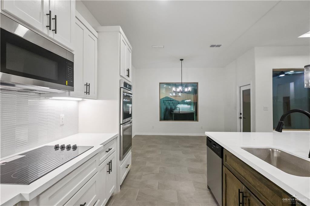 7305 North 55th Lane Mission, TX 78573 - Photo 5 of 26 a kitchen with stainless steel appliances kitchen island a stove a sink and a microwave