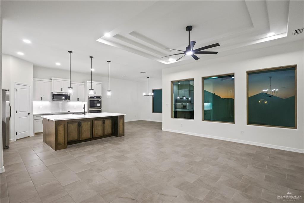 7305 North 55th Lane Mission, TX 78573 - Photo 6 of 26 a large white kitchen with kitchen island a large counter top a sink stainless steel appliances and cabinets