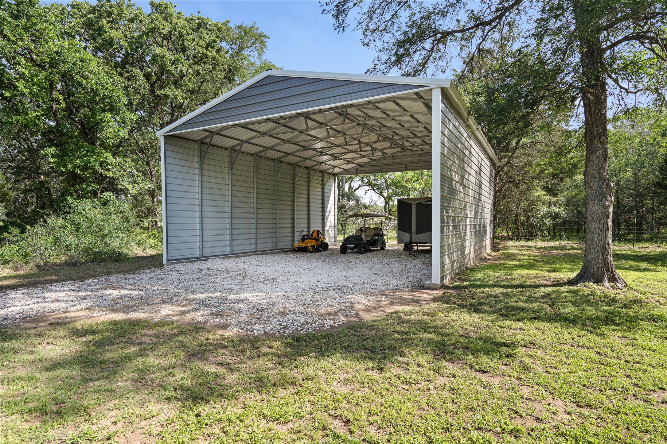 136 Fawn Hollow Elgin, TX 78621 - Photo 39 of 40 Spacious, open-sided metal carport with a gabled roof, offering extensive covered parking