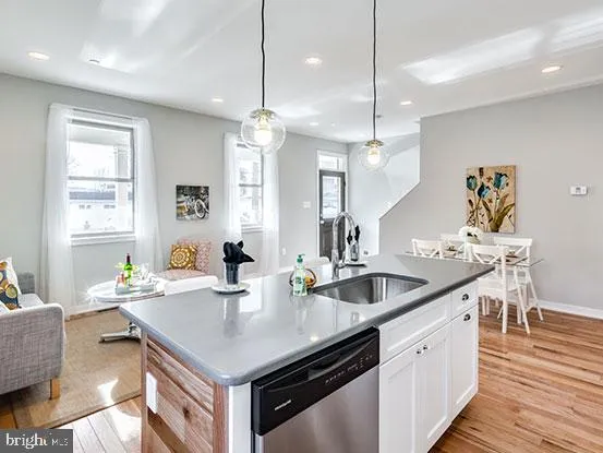 a kitchen with granite countertop a sink a counter space appliances and wooden floor
