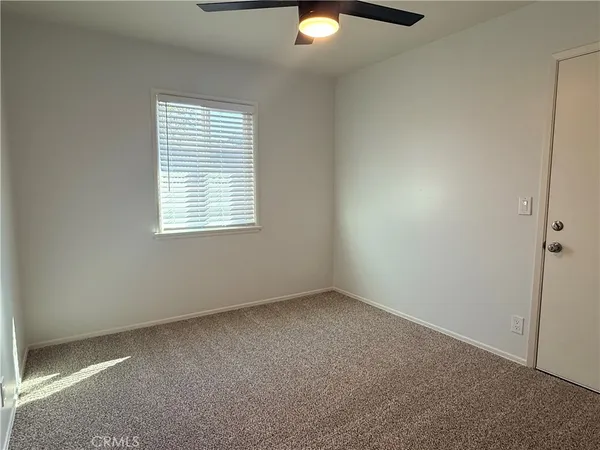 an empty room with a window and a fan