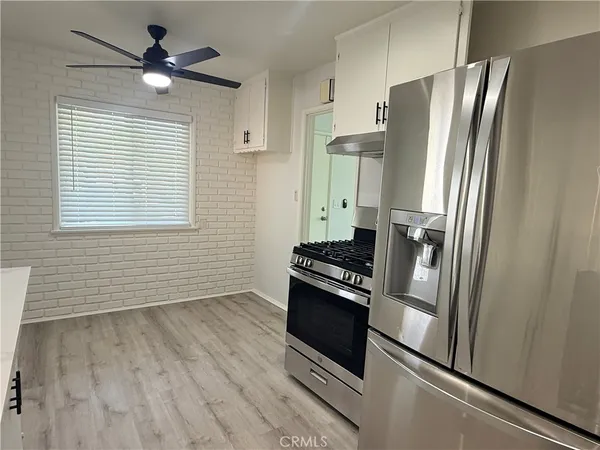 a kitchen with stainless steel appliances granite countertop a refrigerator a stove a sink and a window