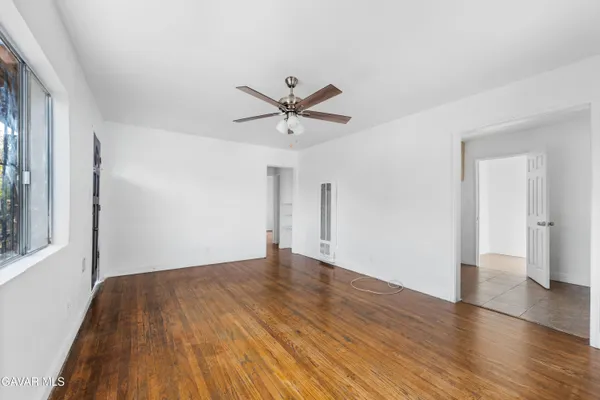 an empty room with wooden floor and a ceiling fan