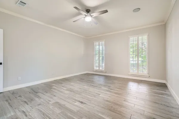 an empty room with wooden floor and windows