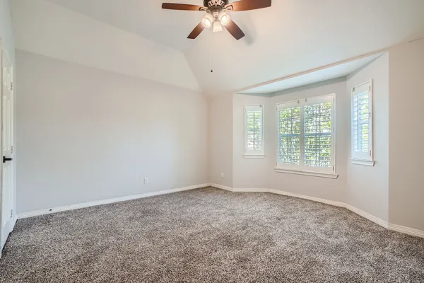 a view of an empty room and chandelier fan