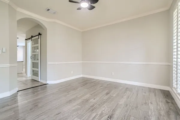 an empty room with wooden floor closet and windows