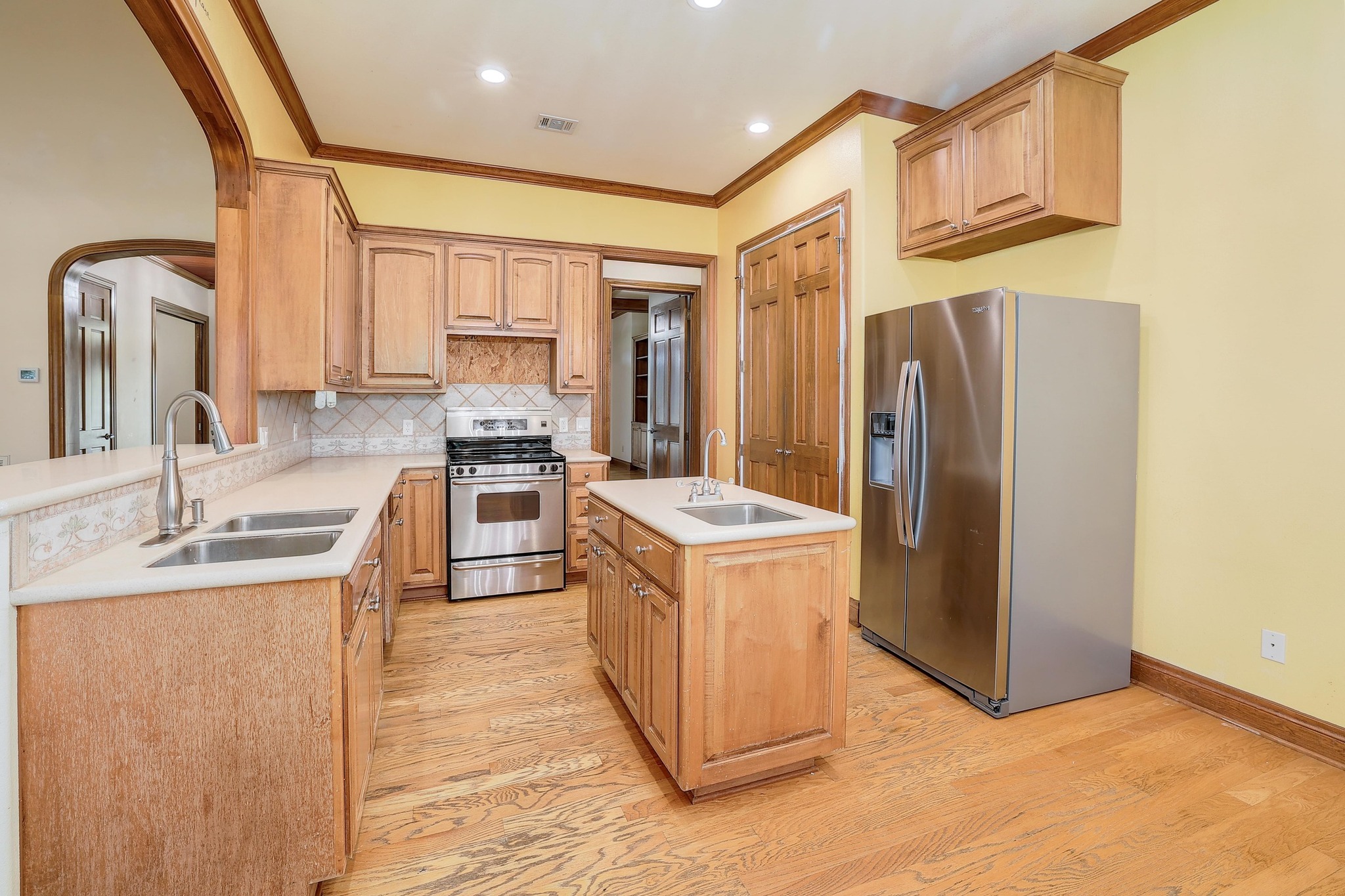 3900 Shell Road Georgetown, TX 78628 - Photo 10 of 40 Kitchen featuring appliances with stainless steel finishes, light wood-type flooring, tasteful backsplash, ornamental molding, and an island with sink