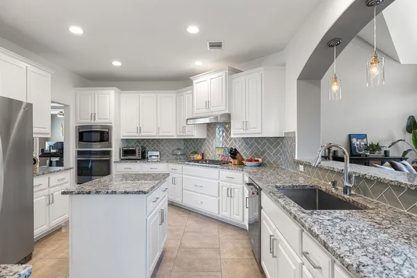a kitchen with stainless steel appliances granite countertop a sink stove and refrigerator