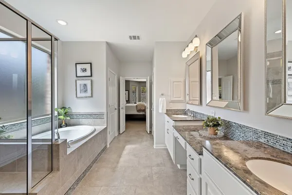 a bathroom with a granite countertop tub sink and mirror