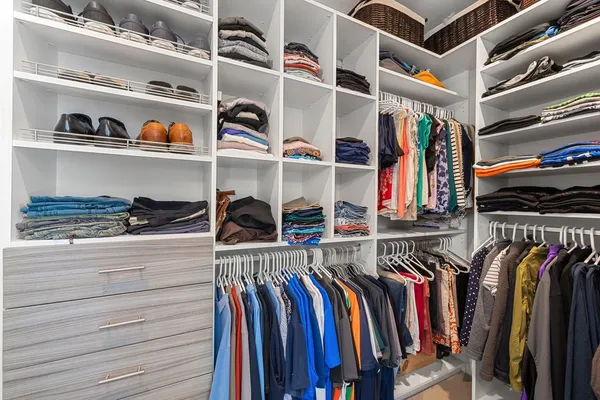 a view of walk in closet with clothes and shoes