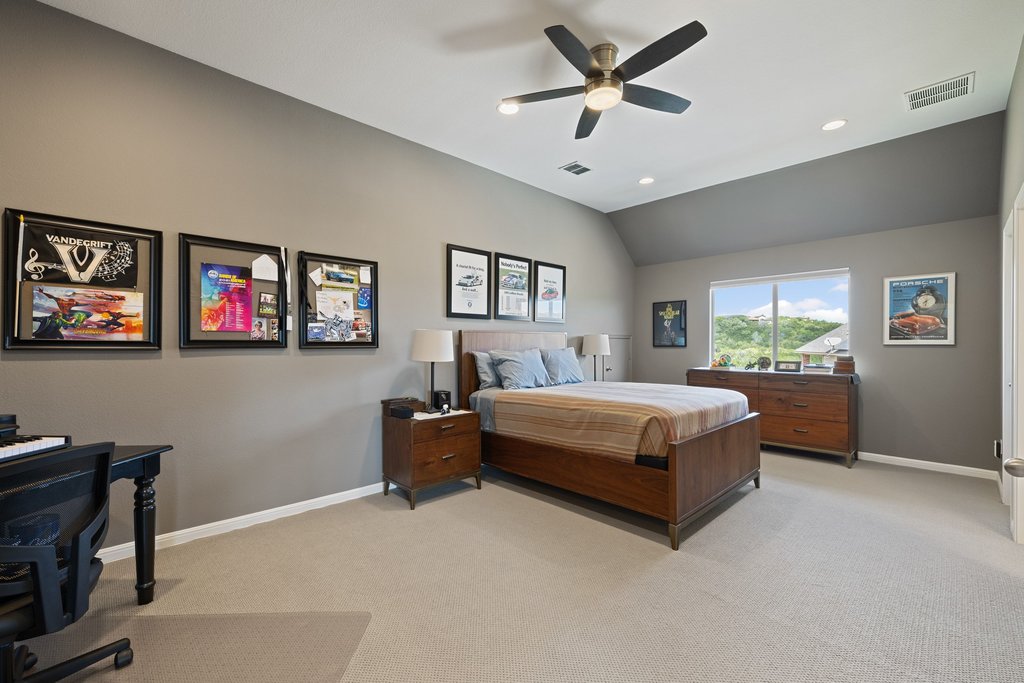 12333 Labrador Bay Court Austin, TX 78732 - Photo 24 of 40 a bedroom with a large bed chandelier and a window