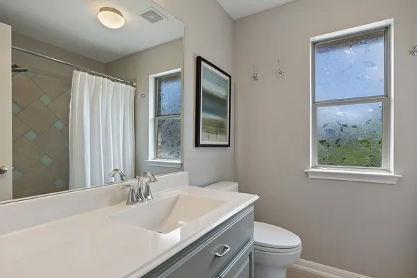 a bathroom with a granite countertop sink mirror vanity and toilet