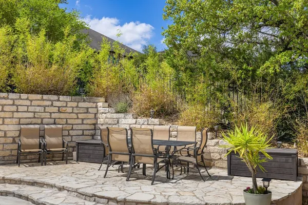 a patio with table and chairs and potted plants
