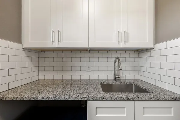 a kitchen with granite countertop white cabinets and a sink