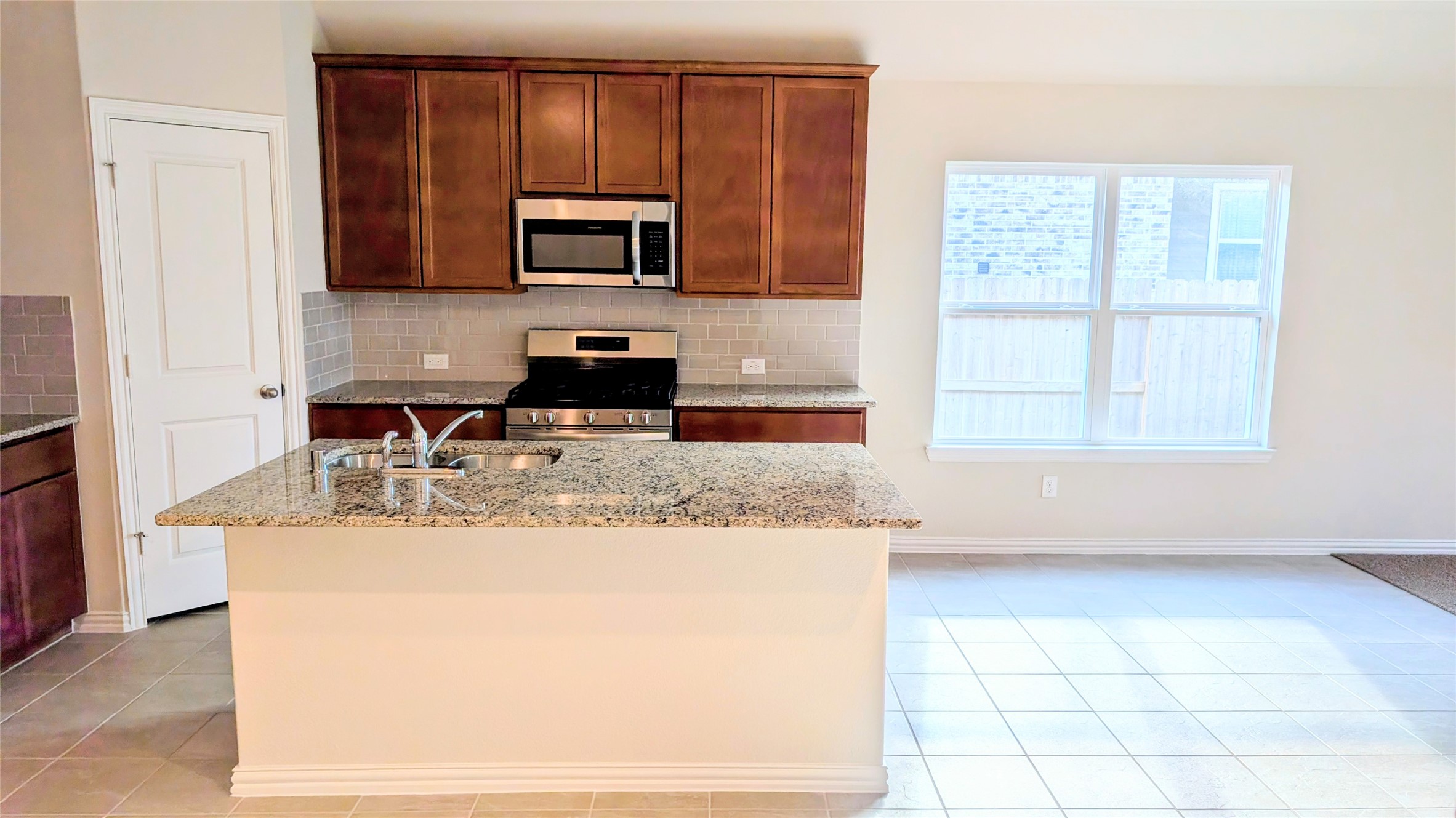 32314 Mimosa Ridge Lane Waller, TX 77484 - Photo 3 of 16 a kitchen with kitchen island granite countertop a sink a stove top oven a counter space and cabinets