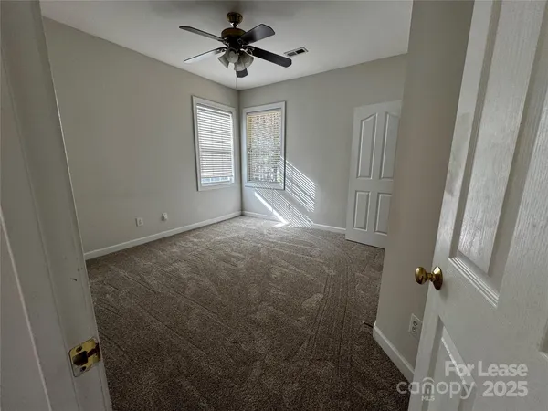 an empty room with windows and chandelier fan