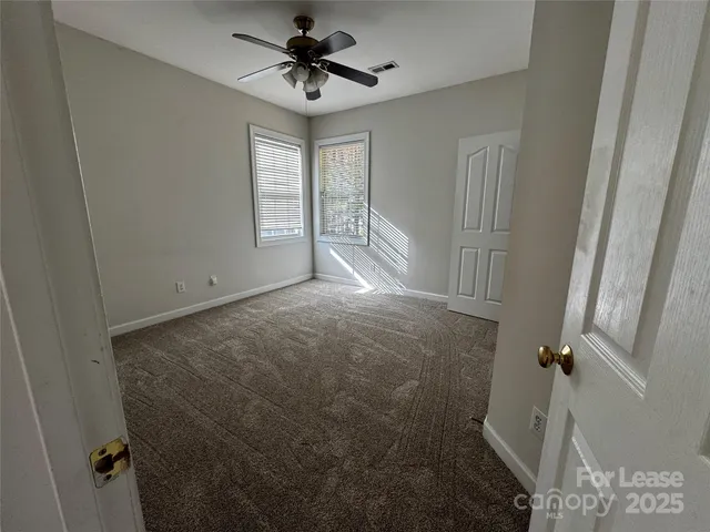 an empty room with windows and chandelier fan
