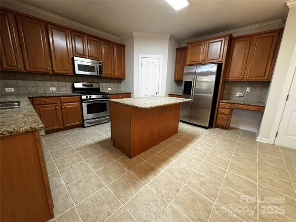 a kitchen with stainless steel appliances granite countertop a stove a sink a refrigerator and a microwave