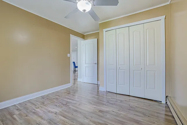 an empty room with wooden floor fan and windows