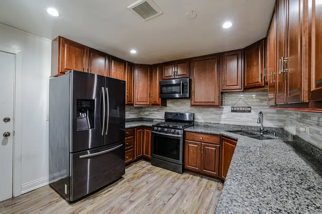 a kitchen with stainless steel appliances granite countertop a refrigerator microwave and wooden floor