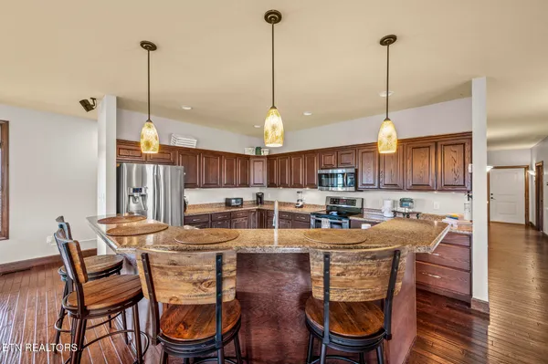 a kitchen with stainless steel appliances granite countertop a sink a stove and a wooden floors