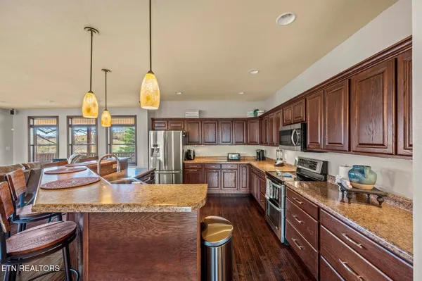 a kitchen with stainless steel appliances granite countertop a stove oven and a dining table with granite countertop chairs