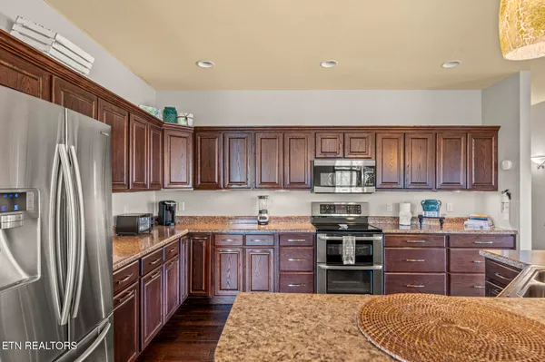a kitchen with stainless steel appliances granite countertop a sink stove and wooden cabinets