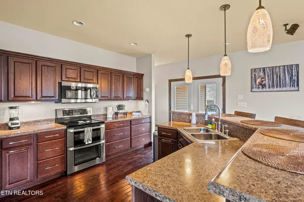 a kitchen with stainless steel appliances granite countertop wooden floors and sink