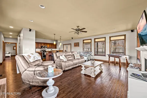 a living room with lots of furniture kitchen view and a wooden floor