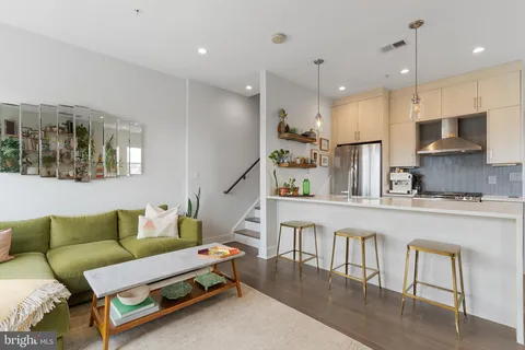 a living room with furniture kitchen view and a wooden floor