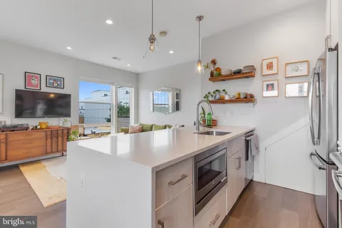 a view of living room kitchen with stainless steel appliances cabinets and flat screen tv