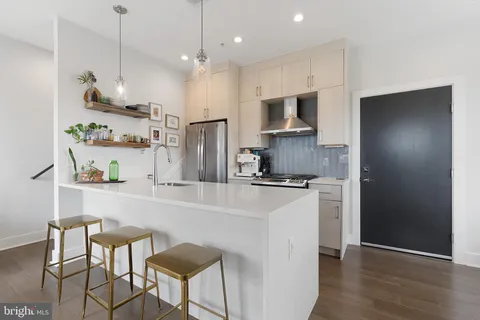 a kitchen with stainless steel appliances granite countertop a refrigerator a sink dishwasher a stove and a refrigerator with wooden floor