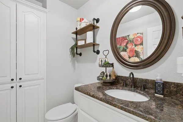a bathroom with a granite countertop toilet a sink and a mirror