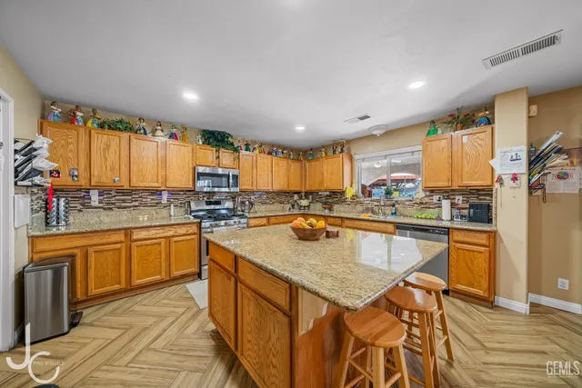 a kitchen with stainless steel appliances granite countertop a stove a sink dishwasher and a refrigerator with wooden floor