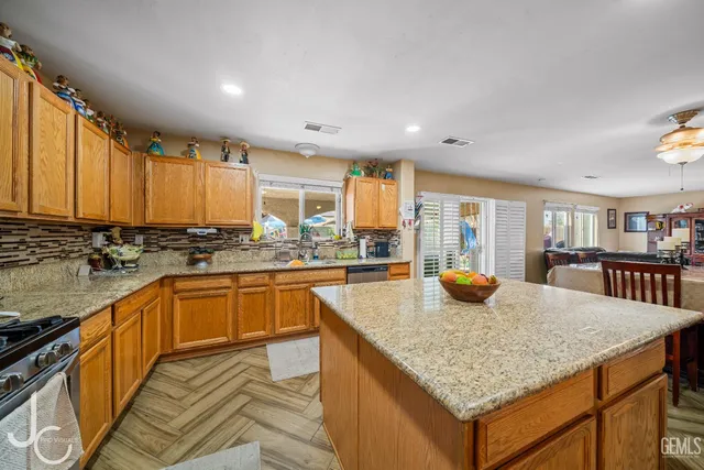 a kitchen with stainless steel appliances granite countertop a kitchen island a stove and a sink